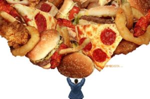 Junk Food Jungle is the reason why the No 1 Killer of this generation are diseases provoked by processed foods, as illustrated by man struggling with a heap of junk food over his head
